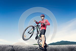 Young man riding mountain bike on the background of mountains at blue sky