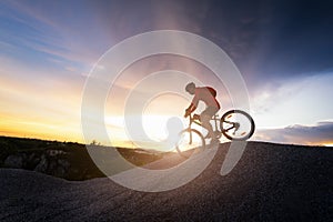 Young man riding mountain bike on the background of mountains at sunset