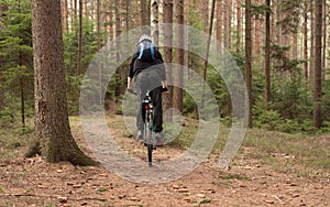 Young man riding a mountain bike throughs the woods.