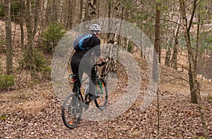Young man riding a mountain bike throughs the woods.