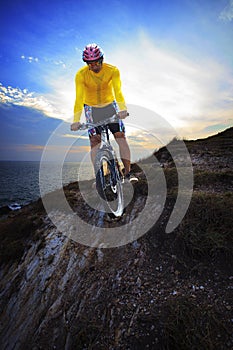 Young man riding moutain bike mtb on land dune against dusky sky photo