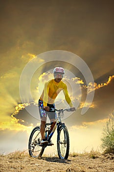 Young man riding moutain bike mtb on land dune against dusky sky in evening background use for sport leisure and out door activit