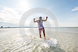 Young man riding on skimboard on summer beach