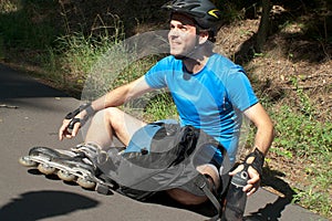 Young man on roller skates sitting resting holding water