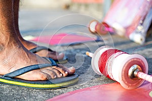 Young man with rubber slippers chappal with a charkhi fikri spool with dor thread with glass thread and kites placed photo
