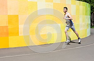 Young man running against bright wall