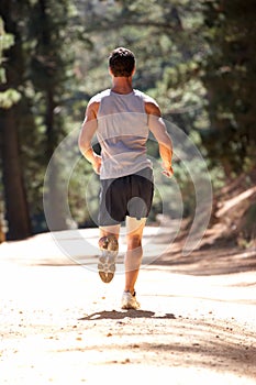 Young man running along country lane photo