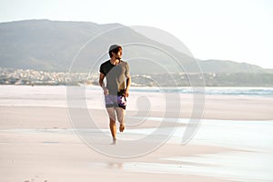 Young man running barefoot on beach
