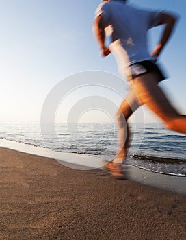 Young man running on a beach at sunrise. Motion blur effect.