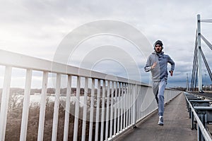 A young man running on the bridge along a river.