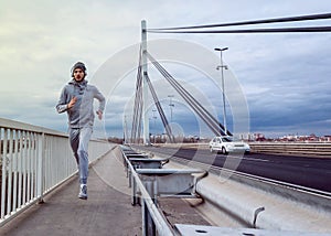 A young man running on the bridge along a river.