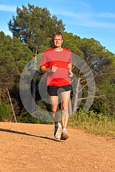 Young man running on the forest road at springtime