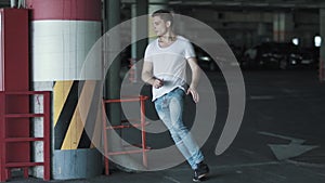 Young man is running and hiding behind column on the underground parking. Slow motion.