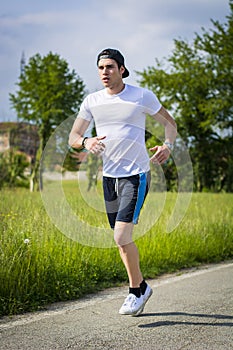 Young man running and jogging on road in country