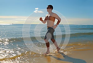 Young man running or jogging on the seachore