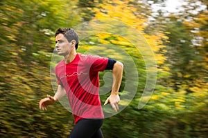 Young man running outdoors in a city park on a fall/autumn day