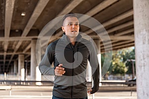 young man running outdoors under bridge