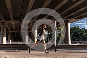 young man running outdoors under bridge