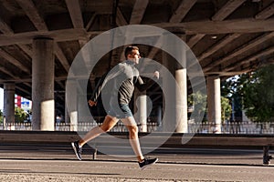 young man running outdoors under bridge