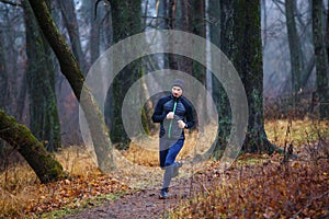 Young man running trail in fall park