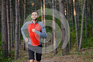 Young Man Running on the Trail in the Wild Pine Forest. Active Lifestyle