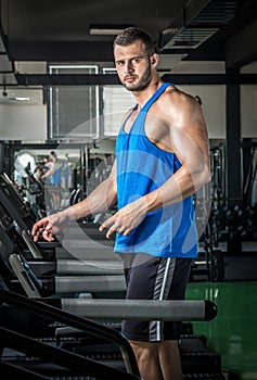 Young man running at treadmill in gym