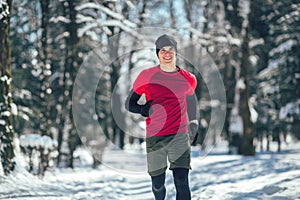 Young man running at winter in park