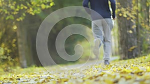 Young man runs in the autumn park. Back view of the sportsman.