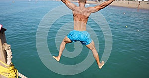 Young man runs and jumps into water from pier