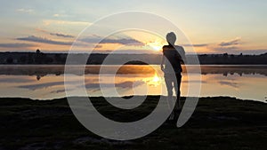 Young man runs from a lake to a cameraman at sunset in slo-mo