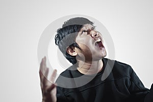 Young man`s face Portrait of a young man screaming and looking up above while standing against.