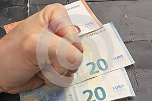 Young man`s fist on a stack of euro banknotes on a black shabby crumpled paper background