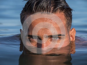 Young man`s half face in water in sea or lake