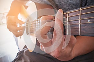 Young man`s hands playing acoustic guitar.The guitar is a fretted musical instrument that usually has six strings.Practicing in