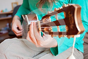 Young man`s hands playing an acoustic guitar ukulele at the home. A man playing ukulele in close up view