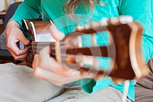 Young man`s hands playing an acoustic guitar ukulele at the home. A man playing ukulele in close up view