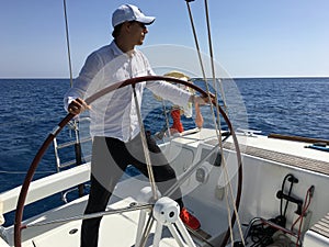 Young man sailing yacht steering wheel vacation