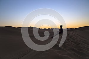 young man on sand in a desert near Huacachina, Ica region, Peru. The sunset desert view