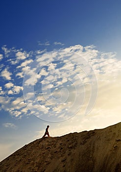 Young man in sand desert in sundown silhouette