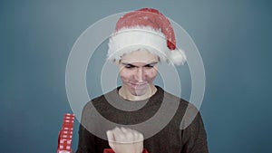 Young man in Santa hat opening a gift box and getting hit on the nose