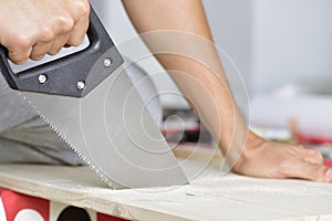 Young man sawing a wooden board with a handsaw photo