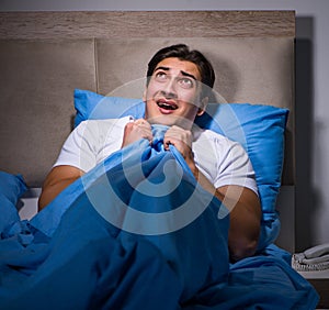 Young man scared in bed