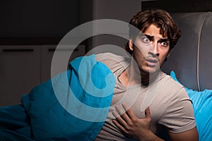 The young man scared in his bed having nightmares