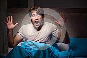 The young man scared in his bed having nightmares