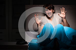 The young man scared in his bed having nightmares