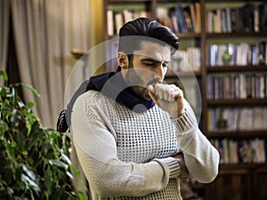 Young man with scarf, holding his neck because of throat ache