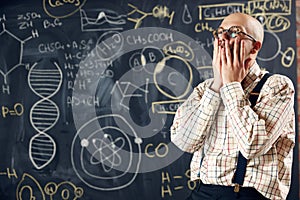 Young man, scientist feeling sad and stressful about unsuccessful researches. Formulas on blackboard