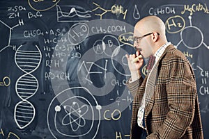 Young man, scientist standing by blackboard with formulas and calculations. Chemistry lessons