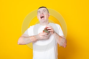 Young man screams in pain, pricked by a cactus on a yellow background. Stress and health concept