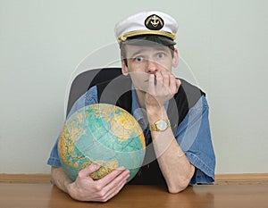 Young man in a sea cap of captain with globe